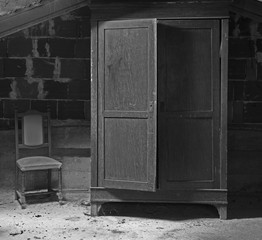 scary closet in the dusty attic with a chair alongside