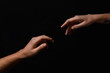 © Pixel-Shot - Male and female hands reaching out to each other on dark background