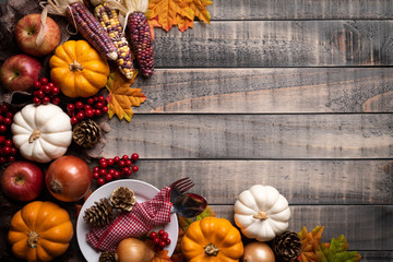 Wall Mural - top view of autumn maple leaves with pumpkin, apple, corn and red berries on old wooden background. 