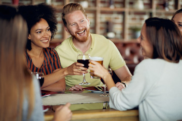 Wall Mural - Friends making a toast while sitting in restaurant. Multi-ethnic group.