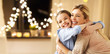 © Syda Productions - holidays, people and family concept - happy smiling girl with mother hugging on sofa at home over garland lights background