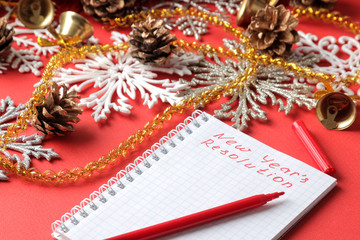 inscriptions New Year's resolution in a notebook and various New Year's decorations on a red background. New Year Christmas. holidays