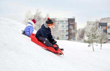 Sticker - childhood, sledging and season concept - happy little kids sliding on sleds down snow hill in winter