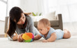 © Syda Productions - family and motherhood concept - happy mother and baby son playing with ball at home