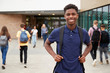© Monkey Business - Portrait Of Smiling Male High School Student Outside College Building With Other Teenage Students In Background