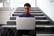 © Monkey Business - Male High School Student Sitting On Staircase And Using Laptop