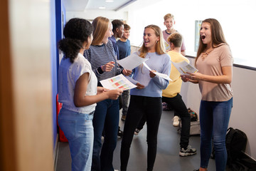 Excited Teenage High School Students Celebrating Exam Results In School Corridor