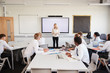 © Monkey Business - Female High School Teacher Standing Next To Interactive Whiteboard And Teaching Lesson To Pupils Wearing Uniform