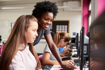 Wall Mural - Teacher Helping Female Pupil Line Of High School Students Working at Screens In Computer Class