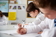 © Monkey Business - High School Students Wearing Uniform Sitting And Working Around Table In Lesson