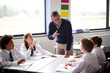 © Monkey Business - Male High School Tutor Standing By Table With Students Teaching Lesson