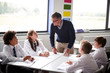 © Monkey Business - Male High School Tutor Standing By Table With Students Teaching Lesson