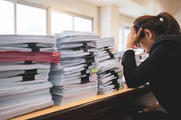 Office woman worker is distressed with a lot of paperwork on her desk.