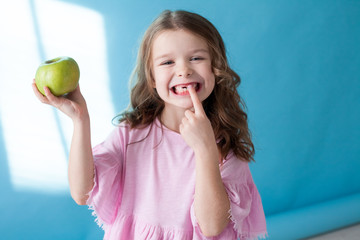 little girl with no teeth eats fruit apple