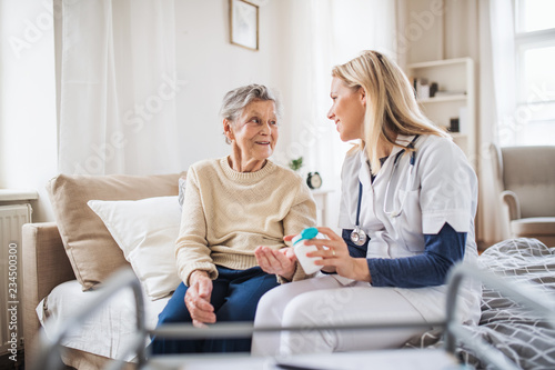 Fotomural A health visitor explaining a senior woman how to take pills.