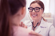 © zinkevych - General practitioner. Pleasant cheerful general practitioner wearing glasses examining cute dark-haired girl
