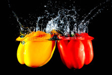 Red And Yellow Peppers Falling In Water, Against Black Background
