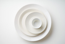 Porcelain Plates Of Various Form And Size On White Background. Overhead Image, Copy Space.