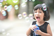 © Asada - Asian little cute girl or kid blow,play air soap bubbles with smile. happiness,fun and childhood concept.