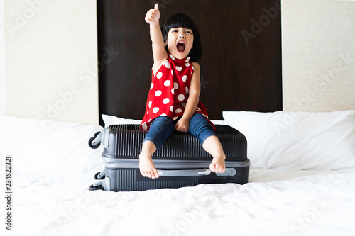 Fotografia Happy Asian cute girl or kid is sitting on the baggage and ready to go to travel in aboard