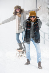 Wall Mural - Young couple playig with sled on winter vacation