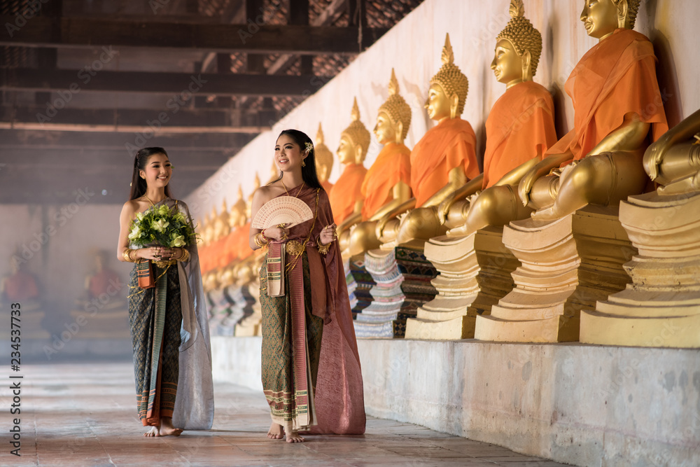 Young beautiful woman in traditional Thai dress costume are walking in the  Buddhist temple and going to worship the Monks at temple during Buddhist  Holy Day. Ayutthaya province, Thailand Stock Photo |