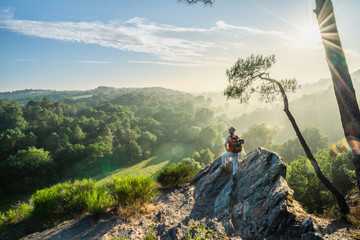 A woman walking on a mountain trail, looks down the valley