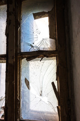 Broken glass in the windows of an old abandoned mystical house. A horror picture of broken window glass. Gloomy interior, depressive background for the design of tragedy, horror, Halloween