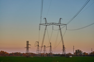 Air high-voltage transmission lines of electric energy over long distances. Overhead lines lay electricity above ground through wires attached to supports. Support, wires and blue sky at sunset