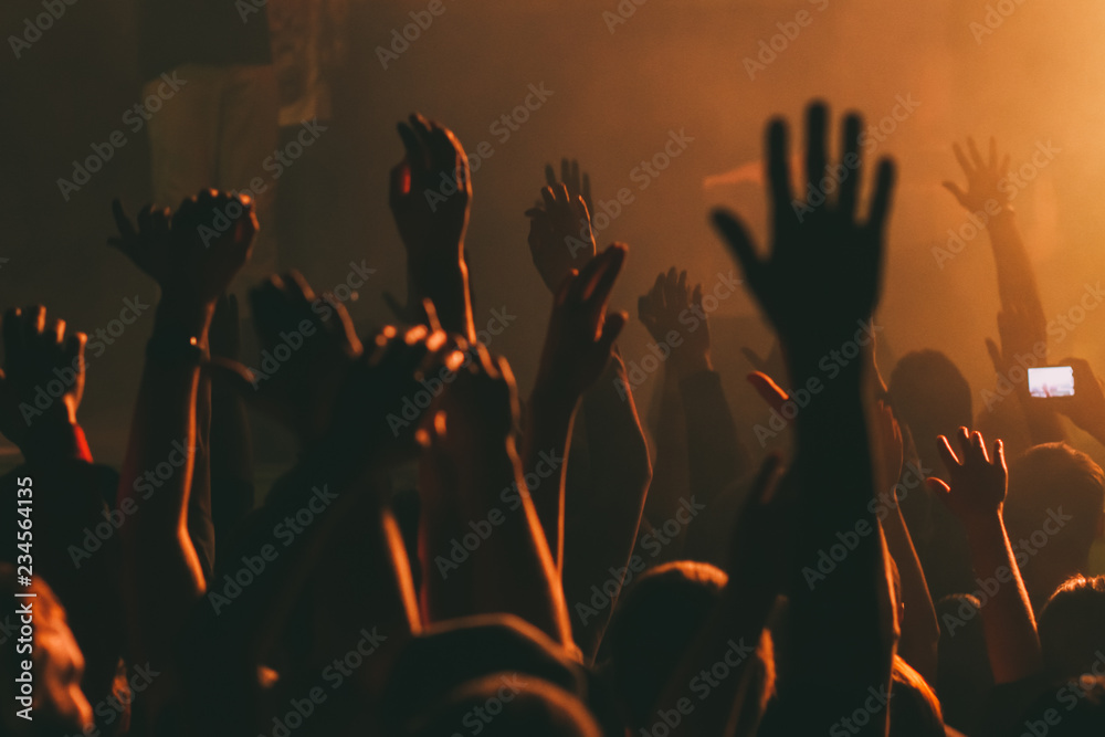 Hands silhouettes of the crowd raised up at music show.  - obrazy, fototapety, plakaty 