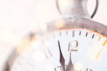 vintage alarm clock is showing midnight. It is twelve o'clock, christmas and bokeh, holiday happy new year festive concept on light bokeh background