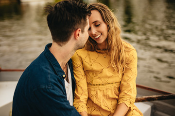 Wall Mural - Close up of a couple in love sitting together near a lake