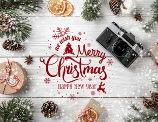 Wall Mural - Christmas and New Year Typographical on white wooden background with Fir branches, gifts, camera. Xmas and Happy New Year theme, snow. Flat lay, top view