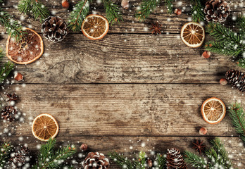 Creative layout frame made of Christmas fir branches, spruce, slices of orange, pine cones, snowflakes on wooden background. Xmas and New Year theme. Flat lay, top view