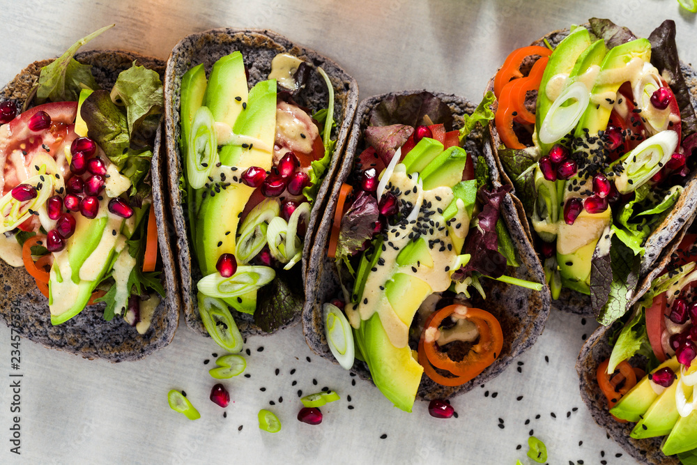 Gluten-free vegan tacos from black bean  with tomato and avocado salad  with tahini sauce and pomegranate seeds. healthy fast food for the whole family or party - obrazy, fototapety, plakaty 