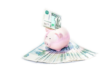 Pink piggy bank with a banknote inserted in the slot in a financial planning, savings and investment concept over a white background