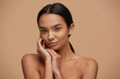 © timtimphoto - Head shot of an attractive mixed race girl, looking gently and tenderly, demonstrates healthy beautiful skin, calm and pleased, keeps hands near the face, over beige background