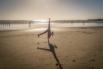 Wall Mural - Girl at Doing Cartwheel on Sand at Beach