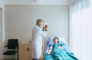 Doctor man working and writing note on saline solution with patient at hospital