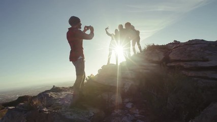 Wall Mural - man taking picture of his friends having fun during hike. group of hikers enjoying themselves and ta