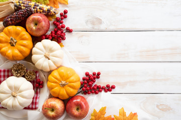 Wall Mural - top view of autumn maple leaves with pumpkin and red berries on white wooden background. thanksgivin