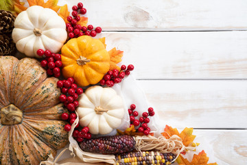 Wall Mural - top view of autumn maple leaves with pumpkin and red berries on white wooden background. thanksgivin