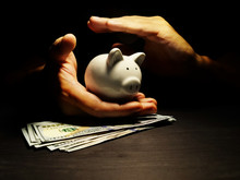 Savings Protection. Hands Protect Piggy Bank With Dollars. Savings Protection.