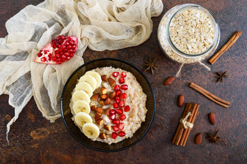 Wall Mural - Delicious and healthy oatmeal with banana, pomegranate seeds, almond and cinnamon. Healthy breakfast. Fitness food. Proper nutrition. Flat lay. Top view.