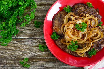 Wall Mural - Juicy slices of fried liver and onions on a red plate. Top view.