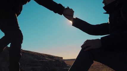 teamwork business travel trip. two men with backpacks hiking help each other silhouette in mountains with sunlight. slow motion video. teamwork friendship hiking help each other trust assistance the