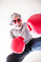 Canvas Print - A senior man with sunglasses and boxing gloves having fun at home.