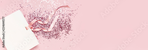Fotografía Flat lay top view White gift bag and holographic glitter confetti in the form of stars on pink background