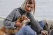 © LIGHTFIELD STUDIOS - beautiful young woman sitting on sofa and holding pembroke welsh corgi dog