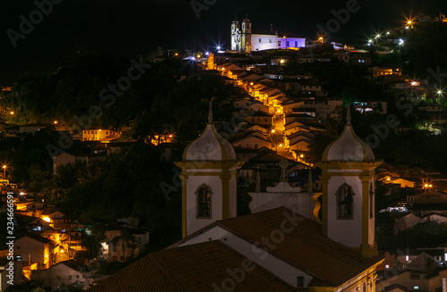 Fotografía Torres da Igreja de Nossa Senhora da Conceição e Igreja de Santa Ifigênia, ao fundo, com ladeira e casario de Ouro Preto, Brasil